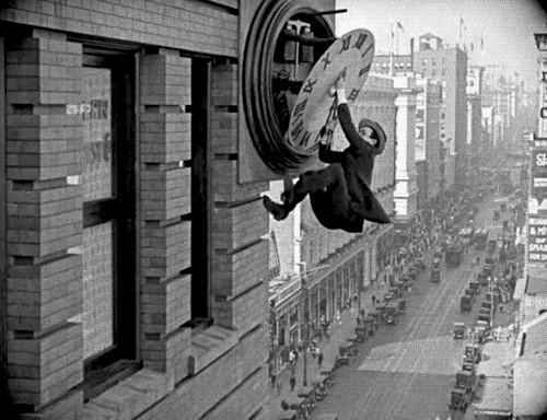 man hanging from clocktower clock face